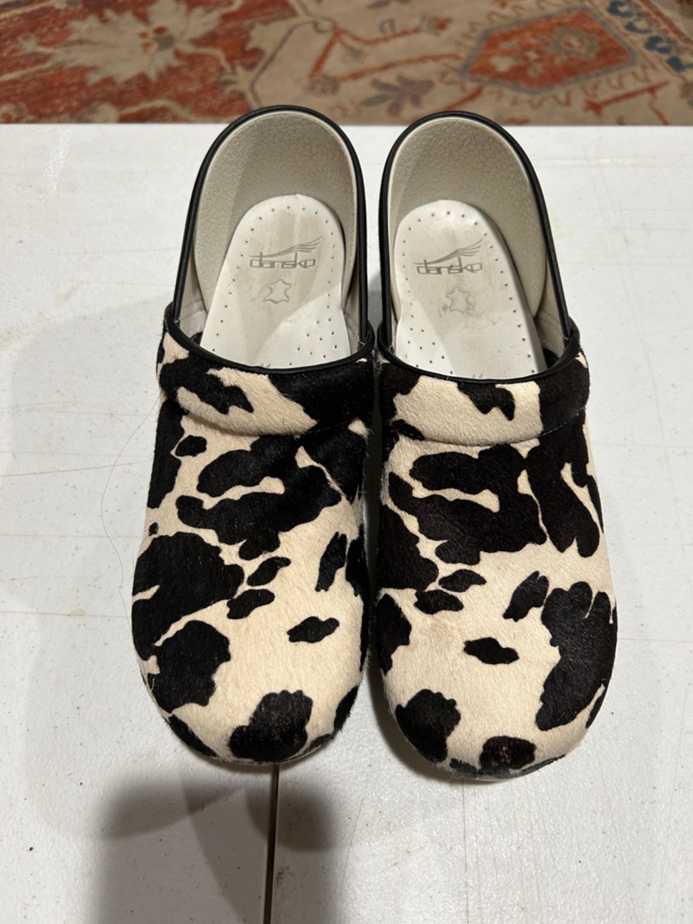 Dansko Cow-Print Clogs in Black and Cream